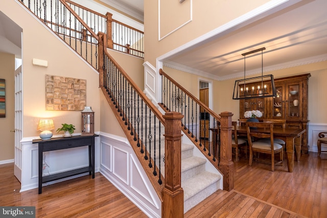 staircase featuring a decorative wall, crown molding, and hardwood / wood-style floors