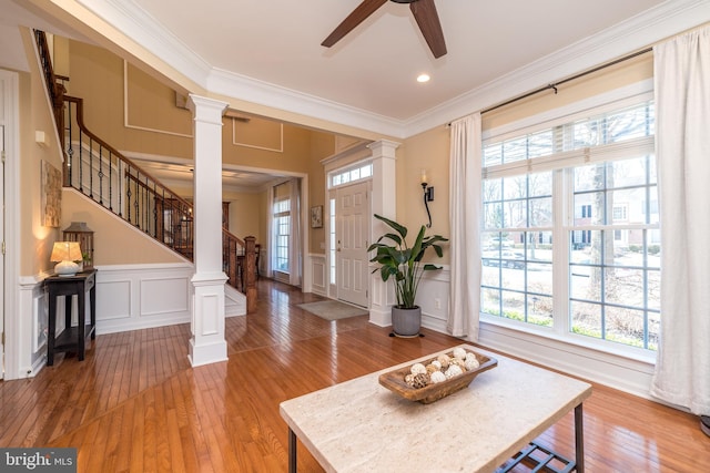 foyer featuring a decorative wall, a healthy amount of sunlight, and ornate columns