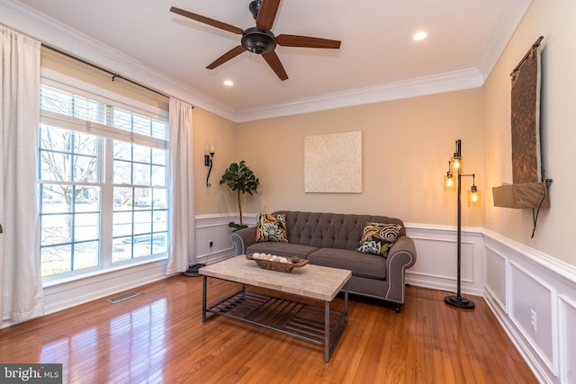 living area with a wealth of natural light, visible vents, and hardwood / wood-style floors