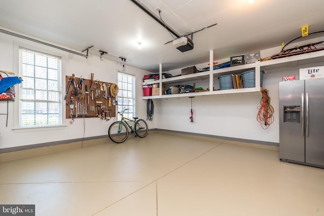 garage featuring baseboards, stainless steel fridge, and a garage door opener