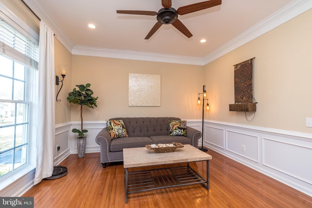 living room with a wainscoted wall, wood finished floors, recessed lighting, crown molding, and ceiling fan