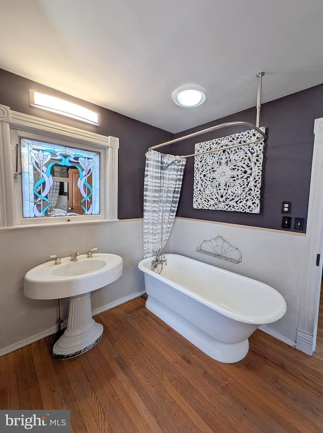 full bathroom with curtained shower, a soaking tub, wood finished floors, and baseboards