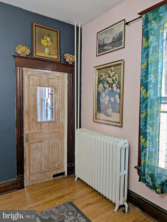 entryway featuring light wood-type flooring, radiator heating unit, and baseboards