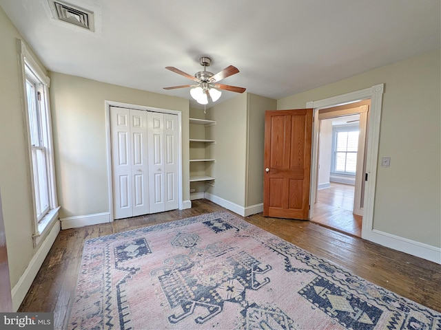 unfurnished bedroom with ceiling fan, wood finished floors, visible vents, and baseboards