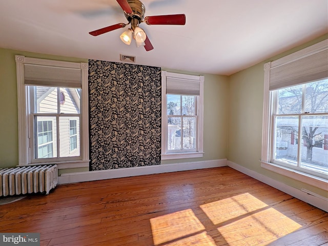 unfurnished room featuring light wood-type flooring, radiator heating unit, visible vents, and baseboards