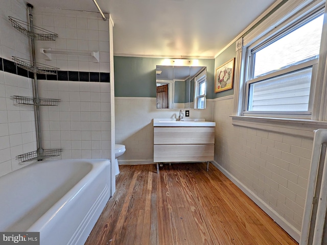 bathroom with a wainscoted wall, tile walls, wood finished floors, and vanity