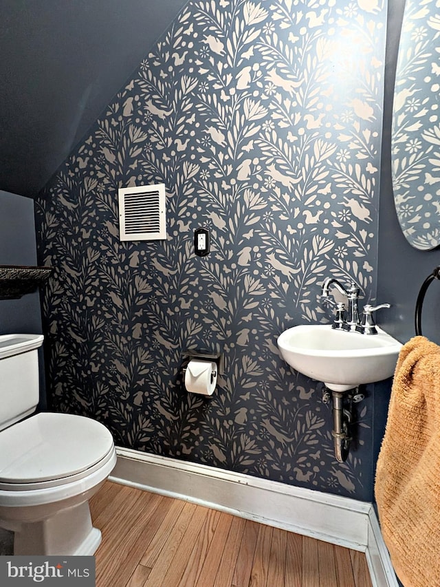 bathroom featuring visible vents, toilet, a sink, wood finished floors, and baseboards