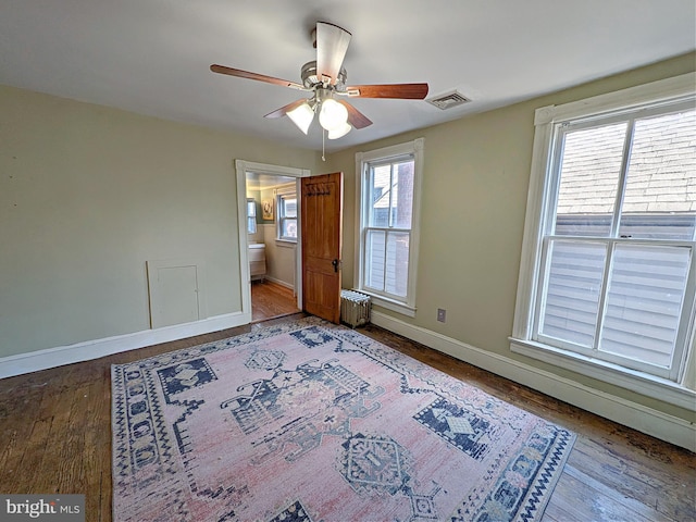 unfurnished bedroom with baseboards, wood finished floors, visible vents, and radiator