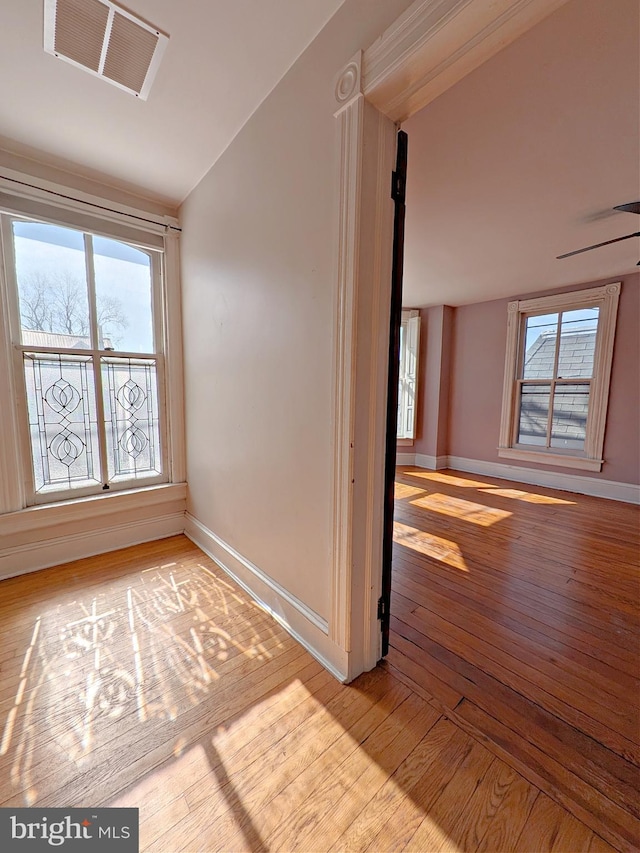 spare room featuring lofted ceiling, light wood finished floors, visible vents, and a wealth of natural light