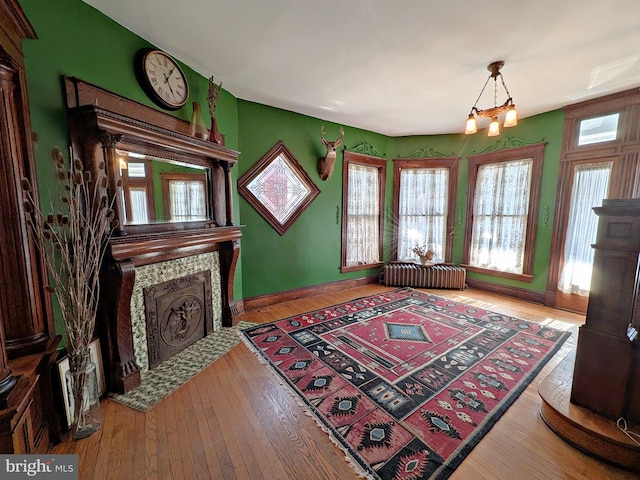 interior space featuring radiator heating unit, a fireplace, baseboards, and wood finished floors