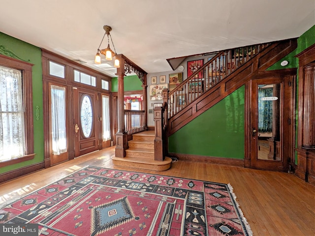 foyer with a wealth of natural light, stairway, and wood finished floors