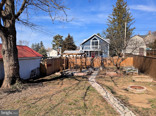 rear view of house with a fenced backyard, a fire pit, and metal roof