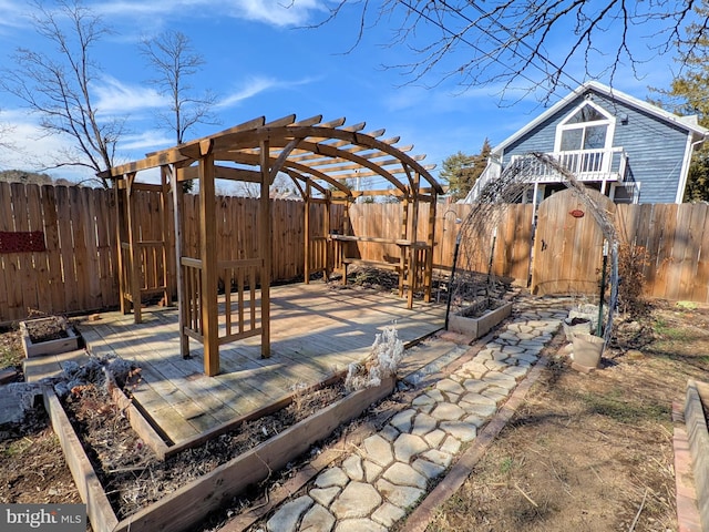 view of patio featuring a deck, a fenced backyard, and a vegetable garden