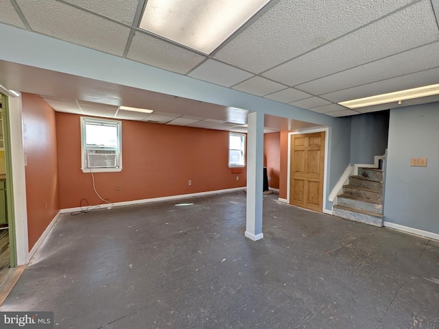 below grade area with stairs, a drop ceiling, cooling unit, and baseboards