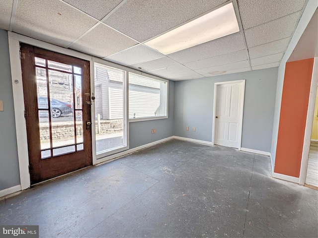 unfurnished room with a drop ceiling, plenty of natural light, and baseboards