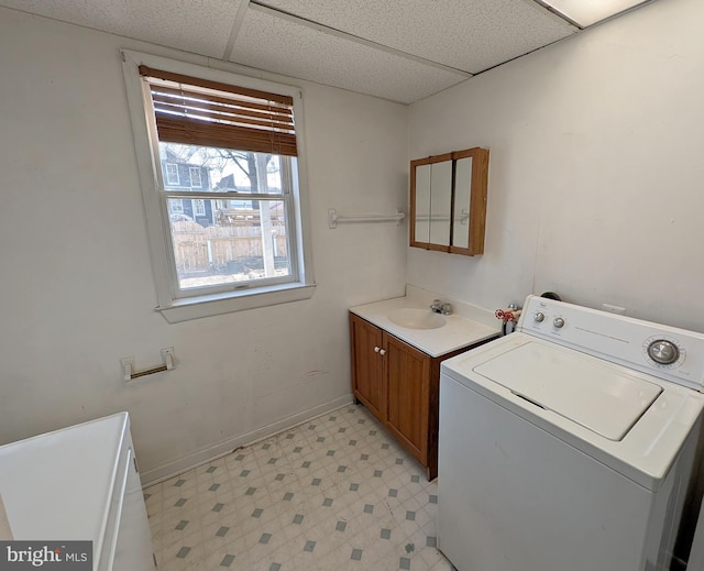 clothes washing area with washer / dryer, laundry area, baseboards, light floors, and a sink