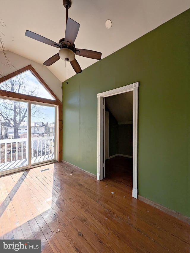 spare room featuring baseboards, visible vents, a ceiling fan, lofted ceiling, and dark wood-type flooring