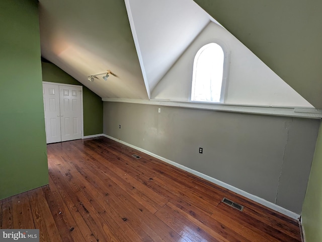 additional living space with lofted ceiling, dark wood finished floors, visible vents, and baseboards