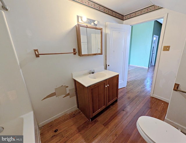 bathroom with toilet, wood finished floors, vanity, and baseboards