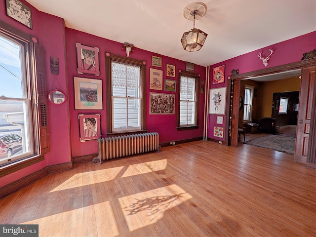 spare room featuring radiator heating unit, plenty of natural light, and wood finished floors