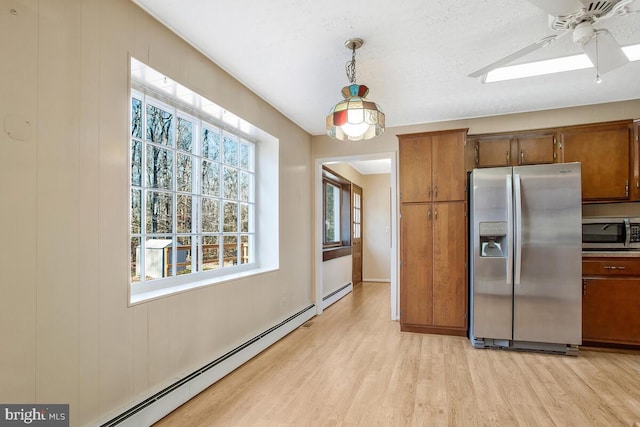 kitchen featuring ceiling fan, appliances with stainless steel finishes, a baseboard heating unit, light hardwood / wood-style floors, and decorative light fixtures