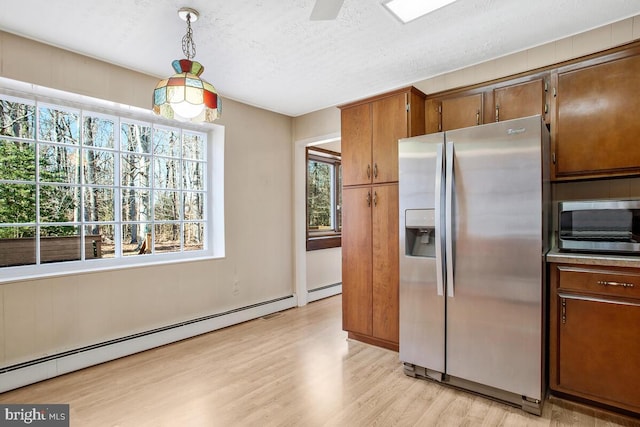 kitchen with a textured ceiling, baseboard heating, stainless steel fridge, pendant lighting, and light hardwood / wood-style floors