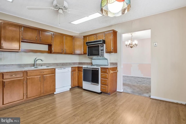 kitchen featuring light hardwood / wood-style floors, sink, white appliances, and decorative light fixtures