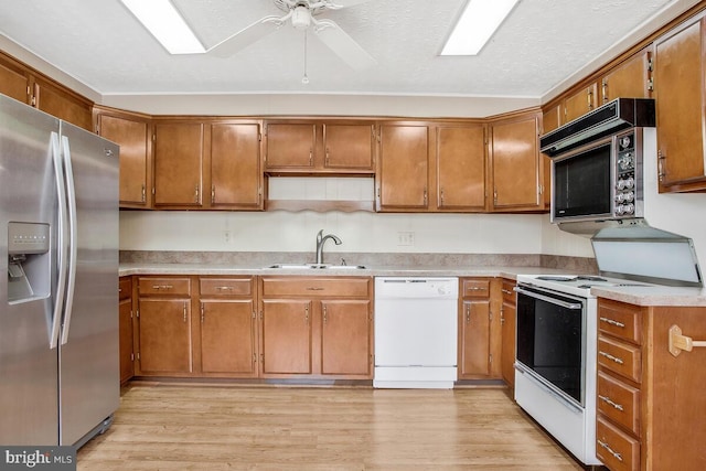 kitchen featuring sink, white appliances, ceiling fan, and light wood-type flooring