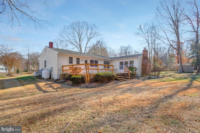 rear view of property featuring cooling unit, a yard, a storage unit, and a deck