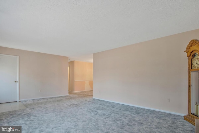 empty room with light colored carpet and a textured ceiling