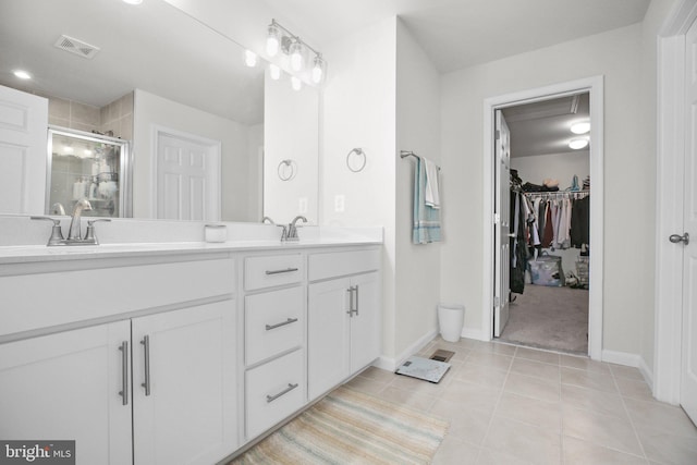 bathroom with double vanity, visible vents, tile patterned floors, a shower stall, and a sink