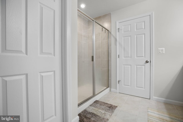 full bath with a stall shower, tile patterned flooring, and baseboards