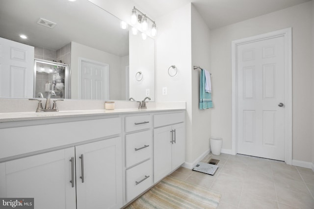 bathroom with double vanity, visible vents, tile patterned floors, a shower stall, and a sink