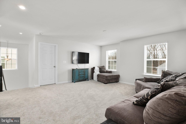 living room featuring baseboards, a healthy amount of sunlight, and light colored carpet