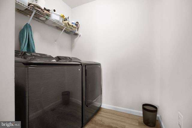 clothes washing area with laundry area, washer and clothes dryer, baseboards, and wood finished floors