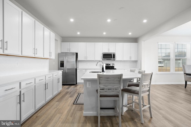 kitchen with stainless steel appliances, light countertops, light wood finished floors, and decorative backsplash