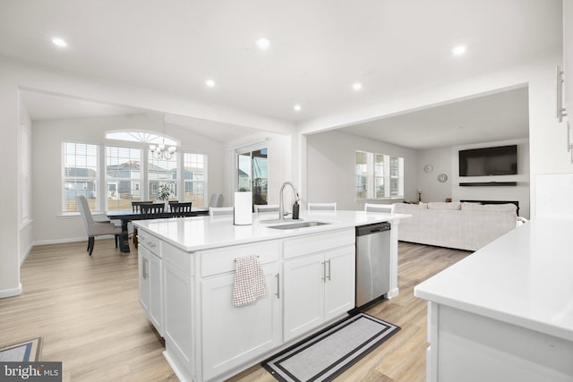 kitchen featuring light countertops, white cabinets, vaulted ceiling, a sink, and dishwasher