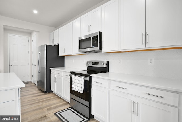 kitchen with white cabinets, light wood-style floors, stainless steel appliances, and light countertops