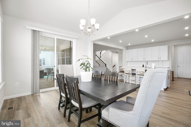 dining area with light wood-type flooring, baseboards, a chandelier, and vaulted ceiling