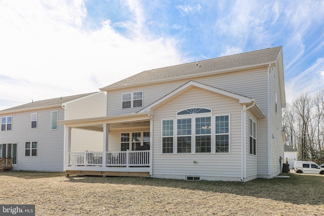 rear view of house with covered porch and a yard