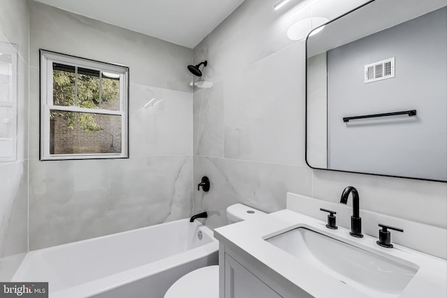 full bathroom featuring tiled shower / bath combo, vanity, tile walls, and toilet