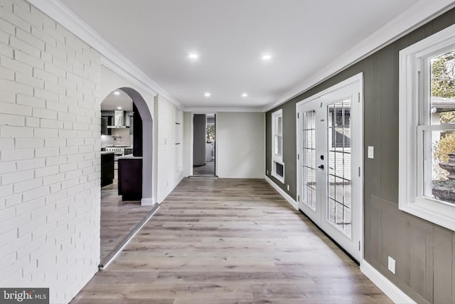 interior space with light hardwood / wood-style flooring, ornamental molding, french doors, and brick wall