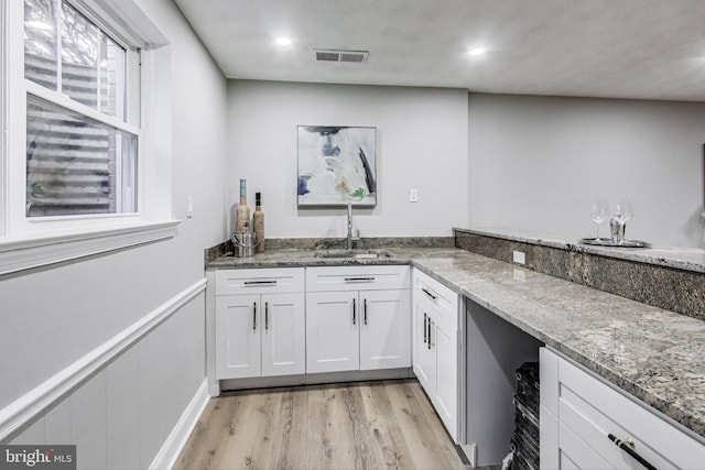 kitchen featuring sink, light hardwood / wood-style flooring, light stone countertops, and white cabinets