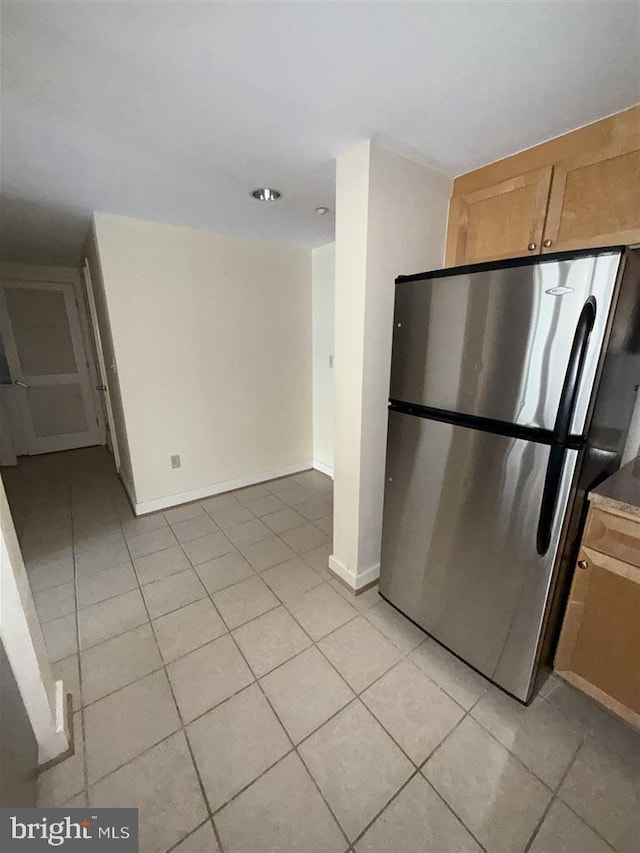 kitchen featuring light tile patterned floors, freestanding refrigerator, and baseboards