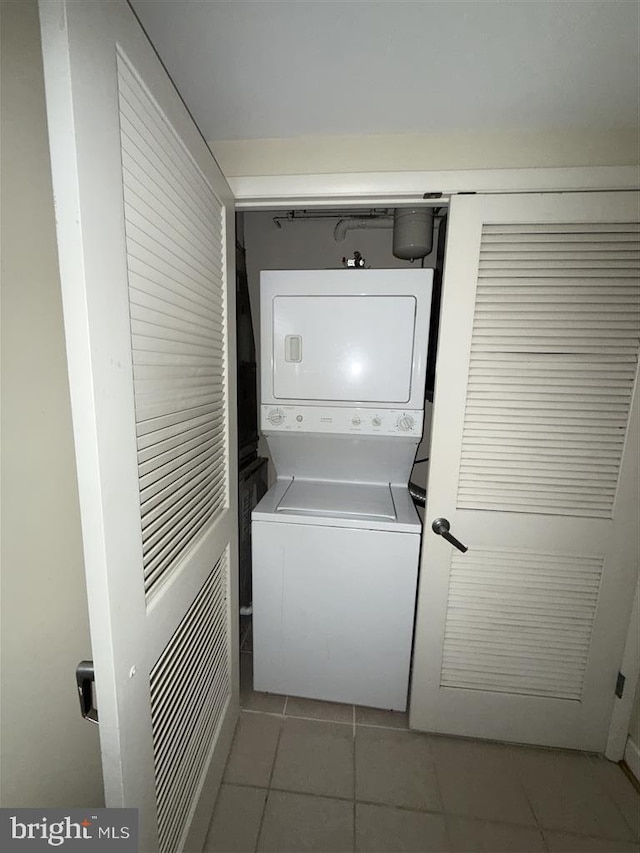 laundry room featuring stacked washer / dryer, laundry area, and light tile patterned floors