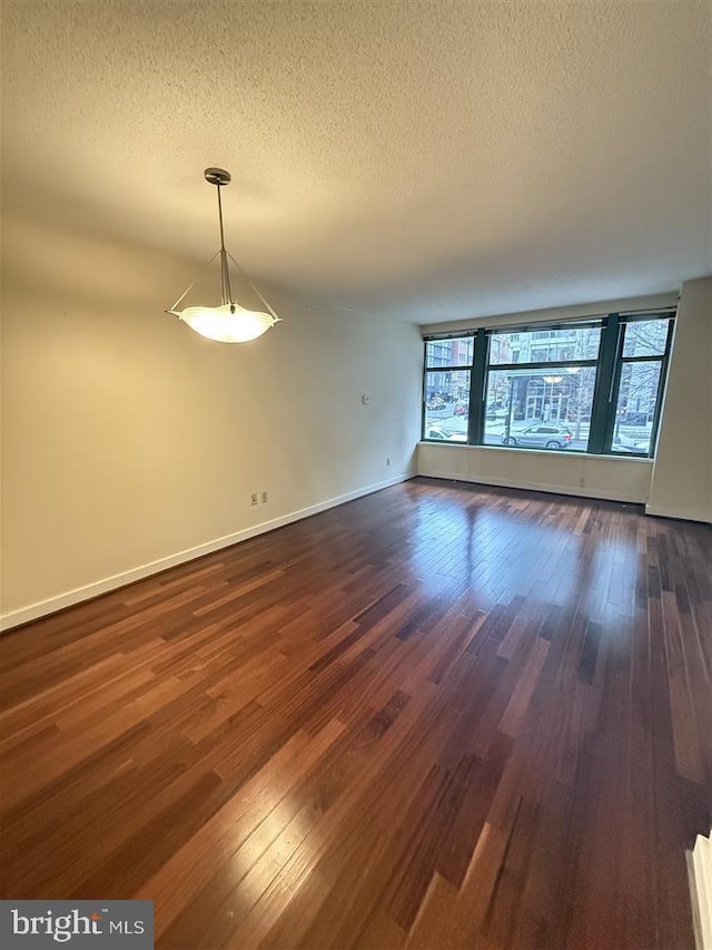 interior space featuring a healthy amount of sunlight, a textured ceiling, and dark wood-type flooring