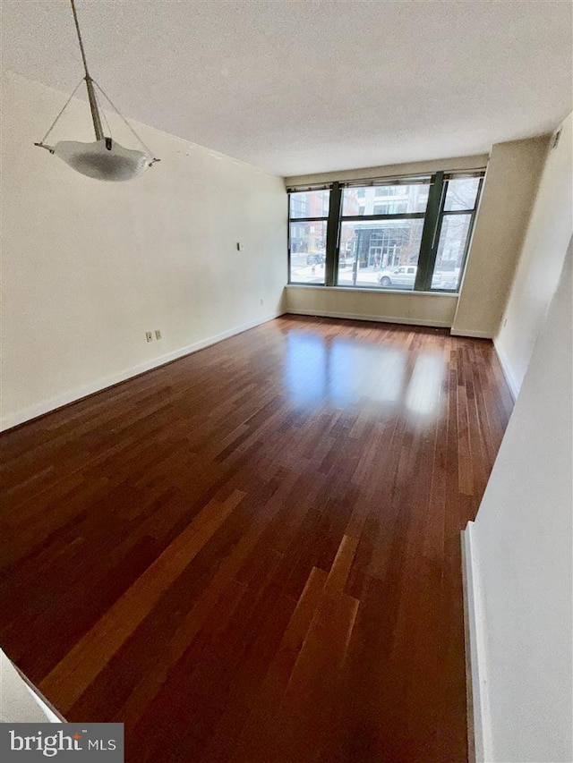 interior space with dark wood-style flooring, a textured ceiling, and baseboards