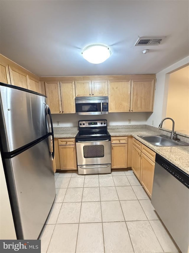 kitchen with light tile patterned floors, stainless steel appliances, visible vents, light brown cabinets, and a sink