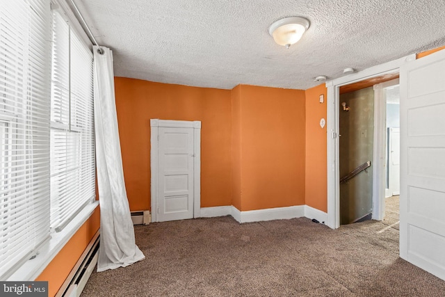 carpeted empty room with a textured ceiling and baseboard heating