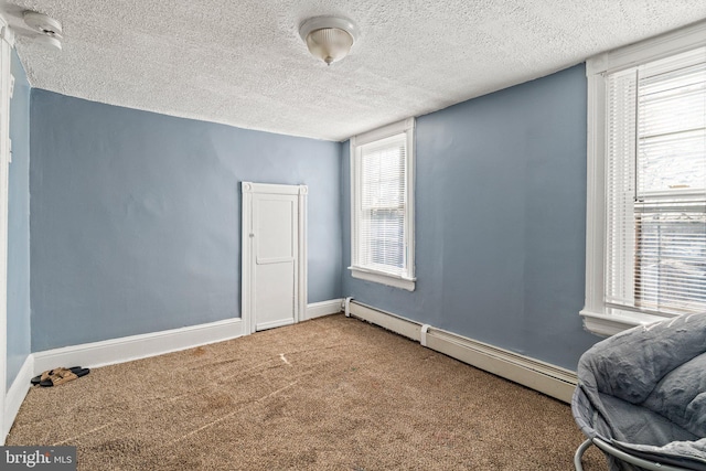 spare room featuring carpet, a textured ceiling, and baseboard heating